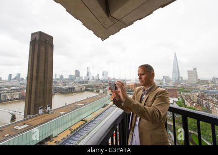 Ein Besucher übernimmt ein Bild von der Aussicht Zentrum von London aus die Galerie in der neuen Schalter Wohnhauserweiterung der Tate Modern in Southwark, London. Stockfoto