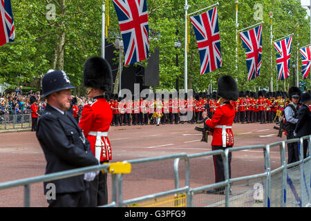 Ein Polizist wacht über die Massen, während die massierten Bands der Gardeabteilung entlang der Mall in Trooping the Color, London, Großbritannien, marschieren Stockfoto