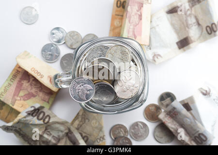 Rupie-Münze in Glas mit Geld streuen um das Glas Stockfoto