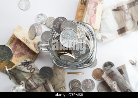 Rupie-Münze in Glas mit Geld streuen um das Glas Stockfoto