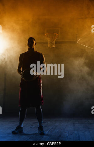 Porträt von einem Basketball-Spieler, einen Ball in den Händen hält Stockfoto