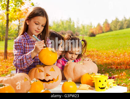 Kleines Mädchen stützt sich auf Halloween-Kürbis Stockfoto