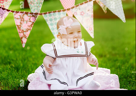 glückliche kleine Mädchen sitzen auf dem Rasen mit Flaggen Stockfoto