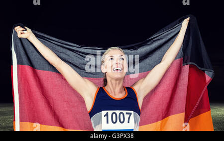 Zusammengesetztes Bild des Athleten posiert mit deutscher Flagge nach Sieg Stockfoto