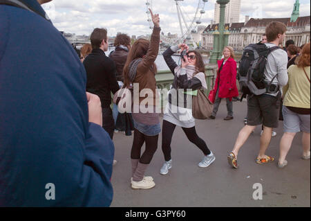 Zwei Touristen auf Westminster Brücke man ein Bild von ihrer Freundin, die in Richtung der Houses of Parliament. Stockfoto