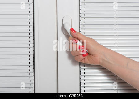 Weibliche Hand und Vorhänge am Fenster Stockfoto