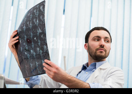 Closeup Portrait des Pflegepersonals intellektuellen Mann mit weißen Laborkittel Gehirn Röntgen Röntgenbild, Ct-Scan, mri, Klinik-Office-Hintergrund zu betrachten. Radiologie Stockfoto