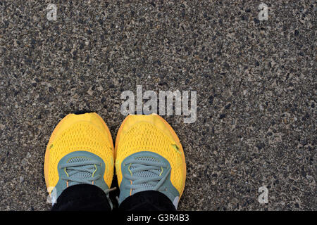 Leuchtend orange Nike Laufschuhe vor konkreten Hintergrund verschlissen. Stockfoto