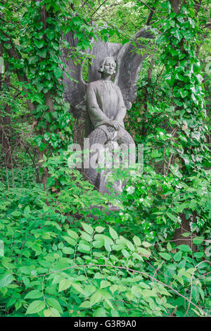 Engelsstatue Grabstein, Ansicht eines Grabes mit einem Steinengel-Grabstein, der von Efeu bewachsen ist, auf dem Kerepesi-Friedhof in Budapest, Europa. Stockfoto