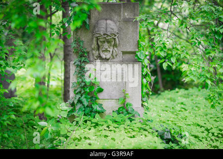 Verlassene Grabstätte, Blick auf einen Grabstein, der mit überwuchertem Unkraut und Efeu bedeckt ist, auf dem Kerepesi-Friedhof in der Gegend von Jozsefvaros in Budapest. Stockfoto