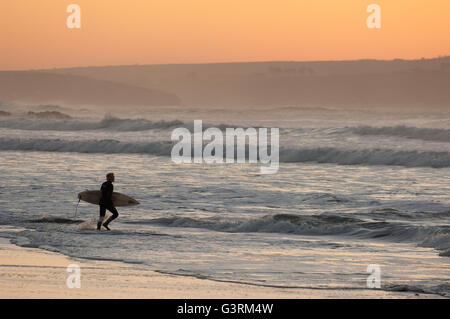 Surfer in der Silhouette, die Eingabe der Wellen bei Sonnenuntergang Stockfoto