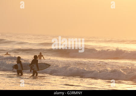 Jugendliche Surfen paar betreten die Wellen im Watergate Bay Beach Stockfoto