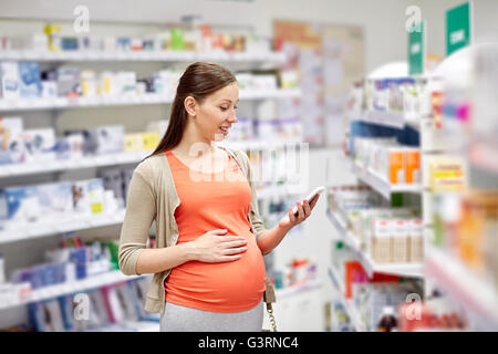 glücklich schwanger Frau mit Smartphone in Apotheke Stockfoto