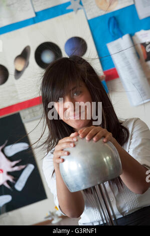 Ein haarsträubendes Schulmädchen mit einem Van-De-Graaff-Generator während ein Physikunterricht. England. UK Stockfoto