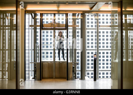 Frau im Glas Aufzug/Lift im modernen Bürogebäude Heron-Tower Stockfoto