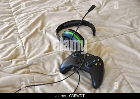 Eine Xbox One Controller und Kopfhörer auf einem Bett Stockfoto