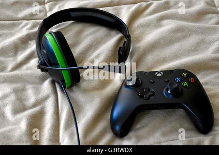 Eine Xbox One Controller und Kopfhörer auf einem Bett Stockfoto