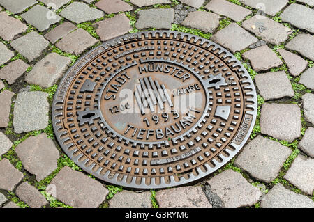 Dekorative Mann-Loch Abdeckung auf gepflasterten Straße in Münster, NRW, Deutschland. Stockfoto