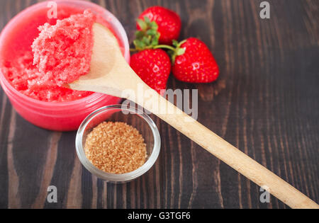 Erdbeer-Körperpeeling mit braunem Zucker auf dem hölzernen Hintergrund Stockfoto