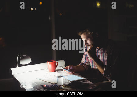 Hipster mit einem Smartphone in der Dunkelheit Stockfoto