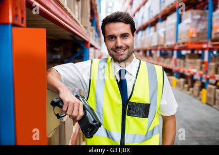 Lächelnde Lagerleiter mit gelben Mantel und scanner Stockfoto