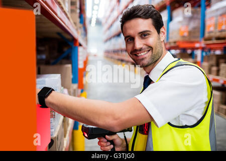 Lächelnd Lagerleiter mit gelben Mantel Scannen von Barcodes auf box Stockfoto