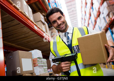 Warehouse Manager mit gelben Mantel Scannen von Barcodes auf box Stockfoto