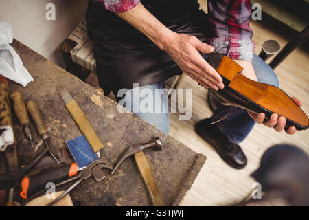 Erhöhte Ansicht der Hände halten einen Schuh Stockfoto