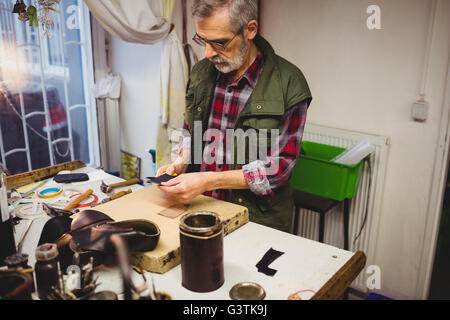 Erhöhte Ansicht der Schuster schneiden ein Stück Leder Stockfoto