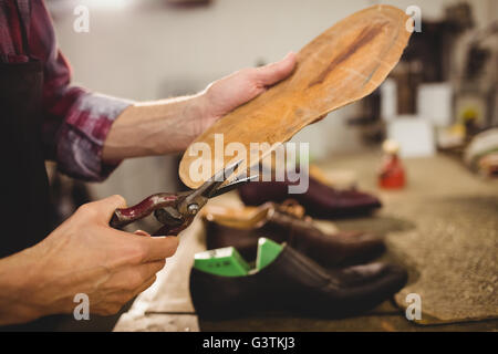 Nahaufnahme von Hand schneiden die Sohle eines Schuhs Stockfoto