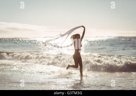 Frau rennt mit Schal am Strand Stockfoto
