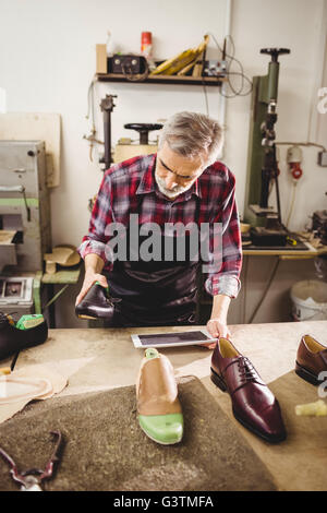 Schuster hält einen Schuh und einem Tablet-computer Stockfoto