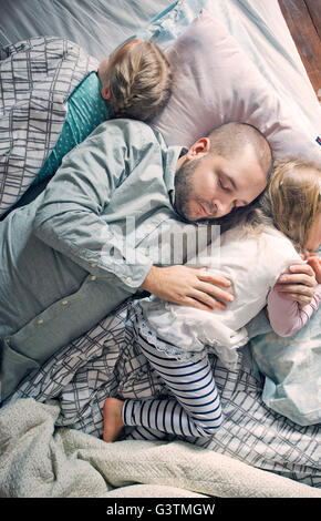 Finnland, Vater schläft mit Töchtern (12-17 Monate, 2-3) auf Bett Stockfoto