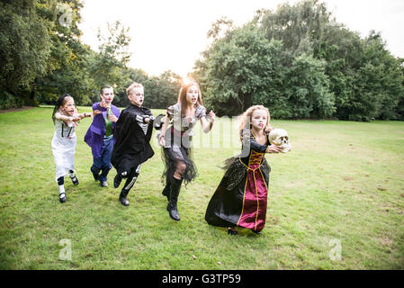 Kinder jagen eine Mädchen gekleidet wie ein Zombie Ballkönigin für Halloween-Nacht. Stockfoto