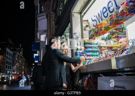 Ein elegant gekleidet paar Kauf von Süßwaren von einem Kiosk auf der Oxford Street in London. Stockfoto