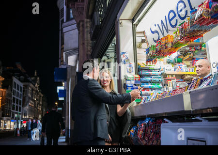 Ein elegant gekleidet paar Kauf von Süßwaren von einem Kiosk auf der Oxford Street in London. Stockfoto