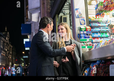 Ein elegant gekleidet paar Kauf von Süßwaren von einem Kiosk auf der Oxford Street in London. Stockfoto