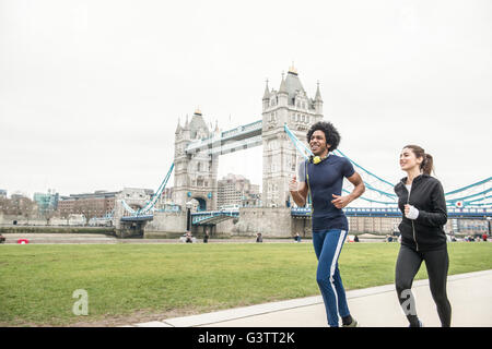 Ein junges Paar, gemeinsam Joggen, vorbei an Tower Bridge in London. Stockfoto