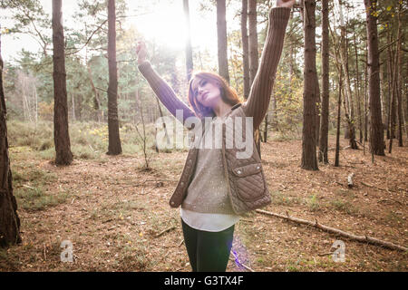 Eine junge Frau, die Zwiesprache mit der Natur in einem Wald im Herbst. Stockfoto