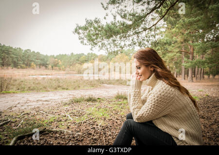 Eine junge Frau, die Zwiesprache mit der Natur auf einem Waldspaziergang im Herbst. Stockfoto