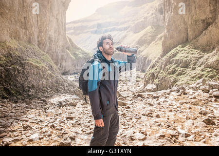Ein Bergsteiger aus seiner Wasserflasche Fin zerklüftete Gelände zu trinken. Stockfoto