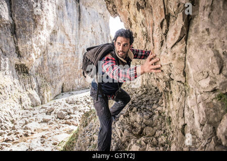 Ein Bergsteiger, einen Felsvorsprung in unwegsamem Gelände zu durchqueren. Stockfoto