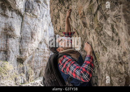 Ein Bergsteiger, einen Felsvorsprung in unwegsamem Gelände zu durchqueren. Stockfoto