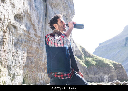 Ein Bergsteiger aus seiner Wasserflasche Fin zerklüftete Gelände zu trinken. Stockfoto