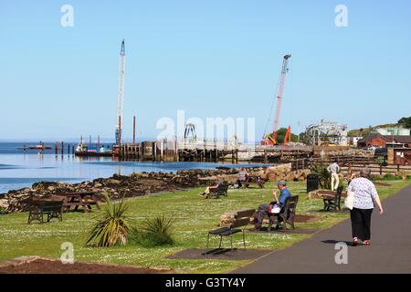Blick entlang Meer bei Brodick gegenüber dem Fährhafen, wo gibt es 2 Kräne auf der Baustelle für das neue terminal Stockfoto
