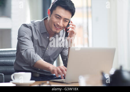 Junger Mann am Telefon im Büro Stockfoto