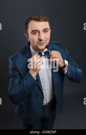 Schöne Moderatorin Mann im blauen Anzug und Fliege mit mic Blick in die Kamera. Schwarzem Hintergrund Stockfoto