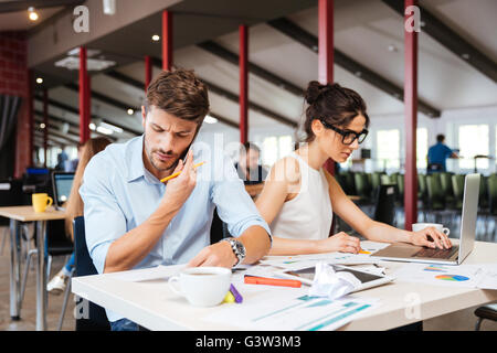 Konzentrierte sich junge Unternehmer und Unternehmerin sitzen und arbeiten im Büro Stockfoto