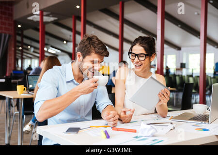 Fröhliche junge Geschäftsleute lachen zusammen und arbeiten im Büro Stockfoto