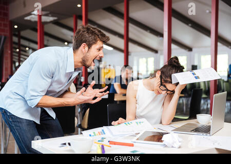 Verrückt crazy junger Geschäftsmann Streit mit traurigen gestresste Geschäftsfrau bei der Arbeit im Büro Stockfoto